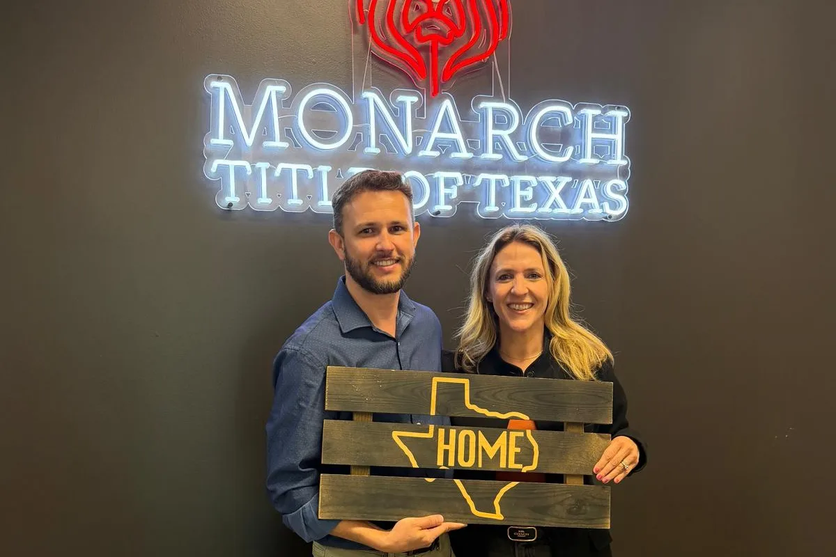 Carina and her client holding a Texas HOME sign on closing day
